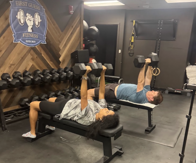 Two members dumbbell bench pressing during semi-private training